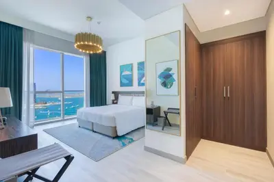 a bedroom with a bed and a desk and windows at Prestige Heights 1BR with Iconic Oceanview in Dubai
