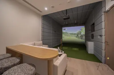 a room with a table and chairs and a golf simulator at Luxe 2BR Maid High Floor LIV Marina Dream in Dubai