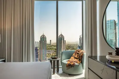 a hotel room with a chair and a large window at Luxe 2BR Maid High Floor LIV Marina Dream in Dubai