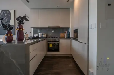 a kitchen with white cabinets and a stove top oven at Luxury Modern 1BR Paragon by Igo Downtown 1BR in Dubai