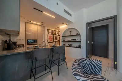 a kitchen with a counter and stools in a room at Luxury 1BR Paragon by IGO BURJ khalifa View in Dubai