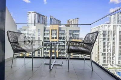 two chairs and a table on a balcony with buildings at Bloomfields Modern STU Azizi Riviera in Dubai