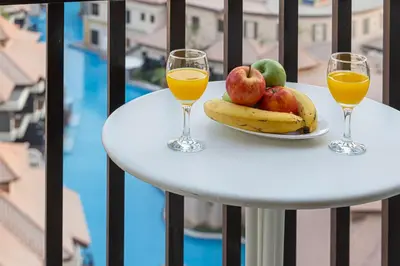 two glasses of orange juice and fruit on a table on a balcony at Luxe Royal Amwaj Palm Jumeirah Beach Access in Dubai