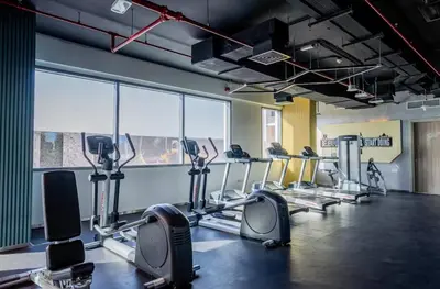 a gym with several treadmills and elliptical machines at Swanky Studio with Balcony in Dubai Hills Estate in Dubai