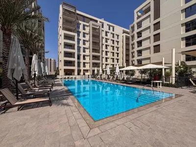 a swimming pool with chairs and umbrellas next to a building at Frank Porter - Grove at Creek Beach Building in Dubai