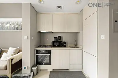 a kitchen with white cabinets and a stove top oven at Elegant 1BR in Business Bay with Pool & Gym in Dubai