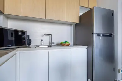 a kitchen with white cabinets and a stainless steel refrigerator at Frank Porter - 5242 Emaar Tower in Dubai