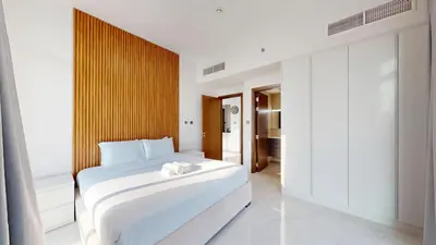 a bedroom with a white bed and a wooden wall at Locations l Peaceful 2 Bedroom l Community Views l Free Pool, Gym Access in Dubai