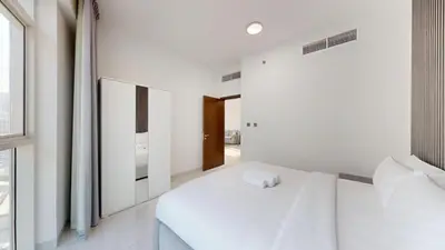 a white bedroom with a bed and a window at Locations l Peaceful 2 Bedroom l Community Views l Free Pool, Gym Access in Dubai