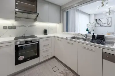 a white kitchen with a sink and a stove at 1 BR Near Burj Khalifa & Dubai Mall - Downtown in Dubai