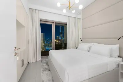 a white bedroom with a large bed and a window at The Iconic View - 3BR With Maid's Room - Burj Khalifa Area in Dubai
