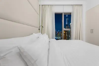 a white bed with a window with a city view at The Iconic View - 3BR With Maid's Room - Burj Khalifa Area in Dubai