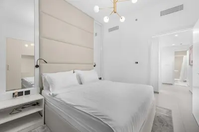 a white bedroom with a bed and a mirror at The Iconic View - 3BR With Maid's Room - Burj Khalifa Area in Dubai