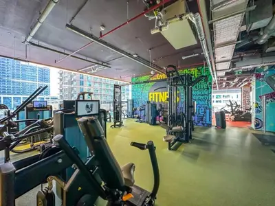a gym with cardio equipment and graffiti on the walls at Luxurious High-Floor 3BR with Assistant Room, Showcasing Lake & City Views, Just Moments Drive from JBR Beaches and Ain Dubai, MBL Royal, JLT by Deluxe Holiday Homes in Dubai