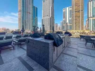 a rooftop patio with tables and chairs in a city at Luxurious High-Floor 3BR with Assistant Room, Showcasing Lake & City Views, Just Moments Drive from JBR Beaches and Ain Dubai, MBL Royal, JLT by Deluxe Holiday Homes in Dubai