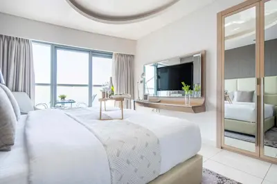 a white bedroom with a large bed and a mirror at Frank Porter - Paramount Tower A in Dubai