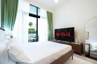 a bedroom with a white bed and a television at Modern Studio in Azizi Riviera 46 with Pool, Gym & Free Parking in Dubai