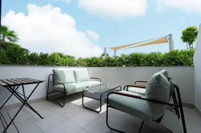 a patio with two chairs and a couch and a table at Modern Studio in Azizi Riviera 46 with Pool, Gym & Free Parking in Dubai