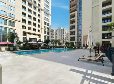a swimming pool with chairs and umbrellas and buildings at Bright 1BR with Balcony Creek Beach Access in Dubai