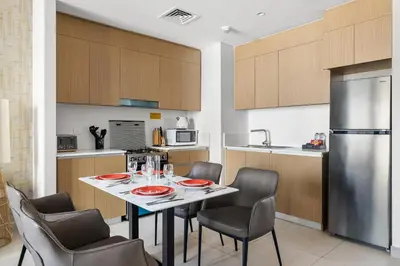 a kitchen with a table with chairs and a refrigerator at Bright 1BR with Balcony Creek Beach Access in Dubai