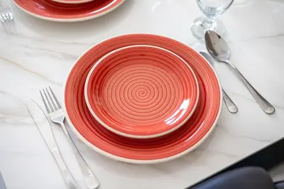 a red plate sitting on a table with silverware at Bright 1BR with Balcony Creek Beach Access in Dubai