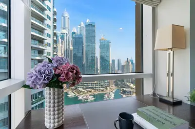 a vase of flowers sitting on a desk in front of a window at The Smart Concierge - Marina tower in Dubai