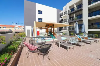a patio with chairs and a table and umbrella at Joya Verde Residence - Studio with Balcony in Dubai