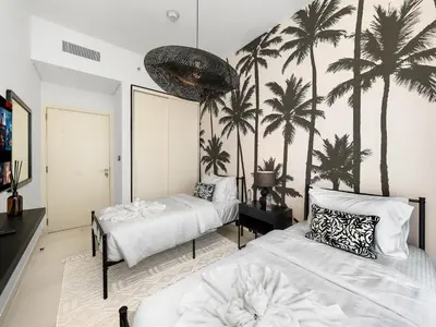 a bedroom with two beds and palm trees on the wall at Modern 2 Bed in Dubai Hills Near Mall & Park in Dubai