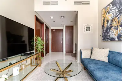 a living room with a blue couch and a glass table at Elegant 1BR Apartment at DAMAC Vera in Business Bay in Dubai