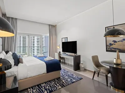 a bedroom with a bed and a desk and a television at Sunlit Studio Haven Luxury Living in Majestine in Dubai