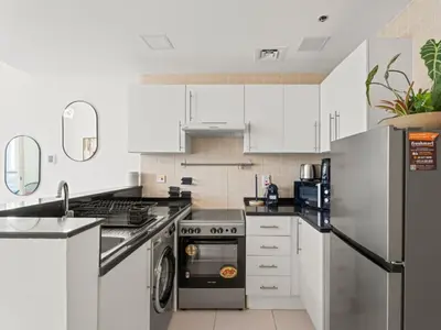 a kitchen with white cabinets and a stainless steel refrigerator at Prime Luxe 1BR w SofaBed -Sleeps 4 - In Marina View in Dubai