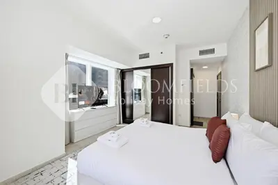a white bedroom with a white bed and a couch at Bloomfields Iconic 2BR Elite Residence Marina in Dubai