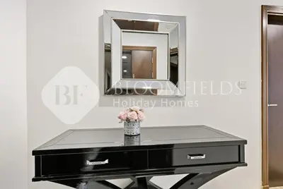 a black vanity with a mirror and a vase of flowers at Bloomfields Iconic 2BR Elite Residence Marina in Dubai
