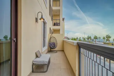 a balcony with a bench and a chair on a building at Port De La Mer by Hosteeva in Dubai