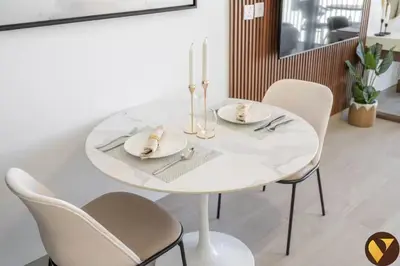 a white dining room table with white plates and chairs at Vogue JVC Luma22 near Circle Mall, Studio Apartment with Balcony and Vibrant Community View, Access to all Amenities in Dubai