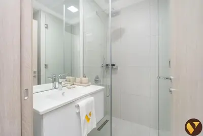 a white bathroom with a sink and a shower at Vogue JVC Luma22 near Circle Mall, Studio Apartment with Balcony and Vibrant Community View, Access to all Amenities in Dubai