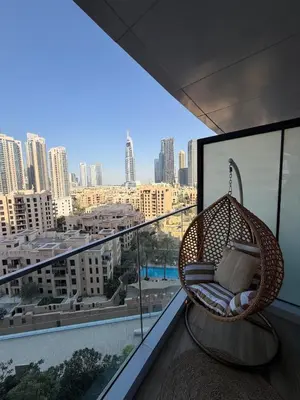 a rattan chair on a balcony with a view of a city at Magical Views Downtown Lux 2 BR Urban Resort in Dubai