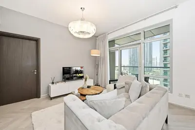 a white living room with a couch and a tv at Ultra Modern Downtown Residence Steps Away from Burj Khalifa and Dubai Mall in Dubai