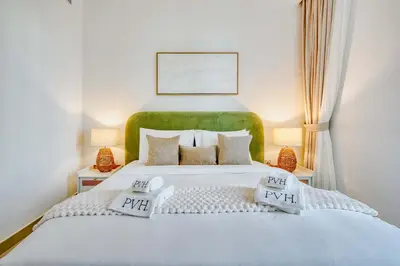 a bedroom with a large white bed with a green headboard at PVH - Serene Central 2BR - Creek Horizon in Dubai