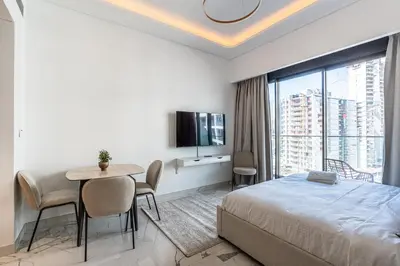 a bedroom with a bed and a table and a tv at Modern Studio Apartment with Outdoor views I Azizi 67 in Dubai