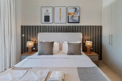 a bedroom with a large white bed with two lamps at Connection to Dubai Mall, 2 King Beds, with Pool, Gym, Tennis Court in Dubai