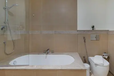 a bathroom with a bath tub and a toilet at Connection to Dubai Mall, 2 King Beds, with Pool, Gym, Tennis Court in Dubai