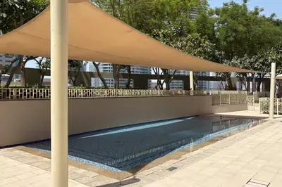a large umbrella over a swimming pool in a building at Connection to Dubai Mall, 2 King Beds, with Pool, Gym, Tennis Court in Dubai
