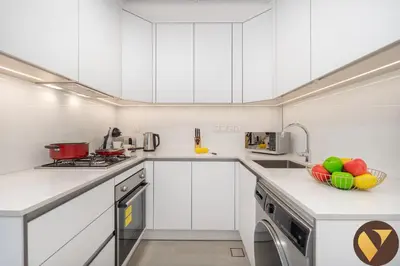 a kitchen with white cabinets and a bowl of fruit on the counter at Vogue JVC Luma22 near Circle Mall, Studio Apartment with Balcony and Vibrant Community View, Access to all amenities in Dubai
