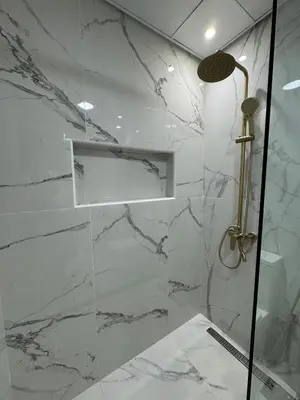 a bathroom with a shower with white marble walls at Smart Studio in Gemz in Dubai