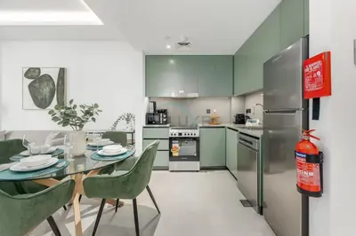 a kitchen with green cabinets and a table and chairs at Prime location near the park, just minutes from the metro, with easy access to all of Downtown Dubai attractions, Viridian, Al Wasl by Deluxe Holiday Homes in Dubai