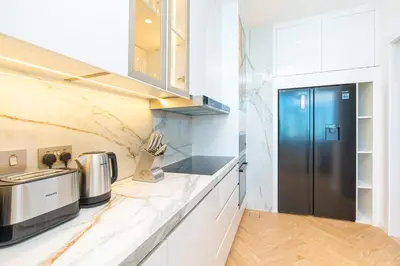 a kitchen with a black refrigerator and white cabinets at PVH - Coastal 2BR with Beach Access - Atlantic Oceana in Dubai