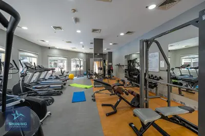a gym with rows of treadmills and machines at Peaceful 1BR JVC Near Circle Mall Pool Gym in Dubai