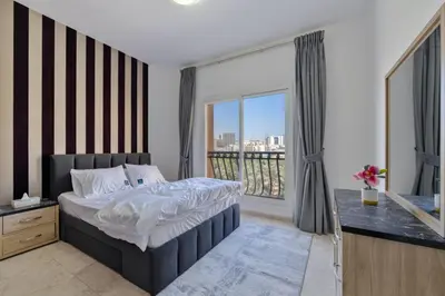 a bedroom with a bed and a large window at Peaceful 1BR JVC Near Circle Mall Pool Gym in Dubai