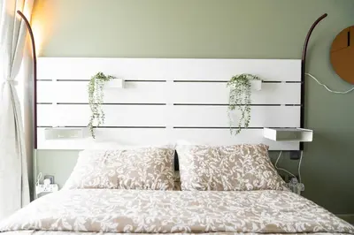 a bed with a white headboard with two plants on it at Meydan Boutique Loft Near Downtown in Dubai